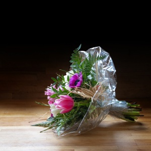 Bouquet of  spring flowers in cellophane on wood, dark backgroun